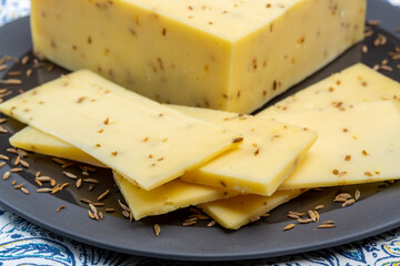 Cheese collection, piece of cow milk Dutch gouda cheese with dried aromatic cumin seeds close up