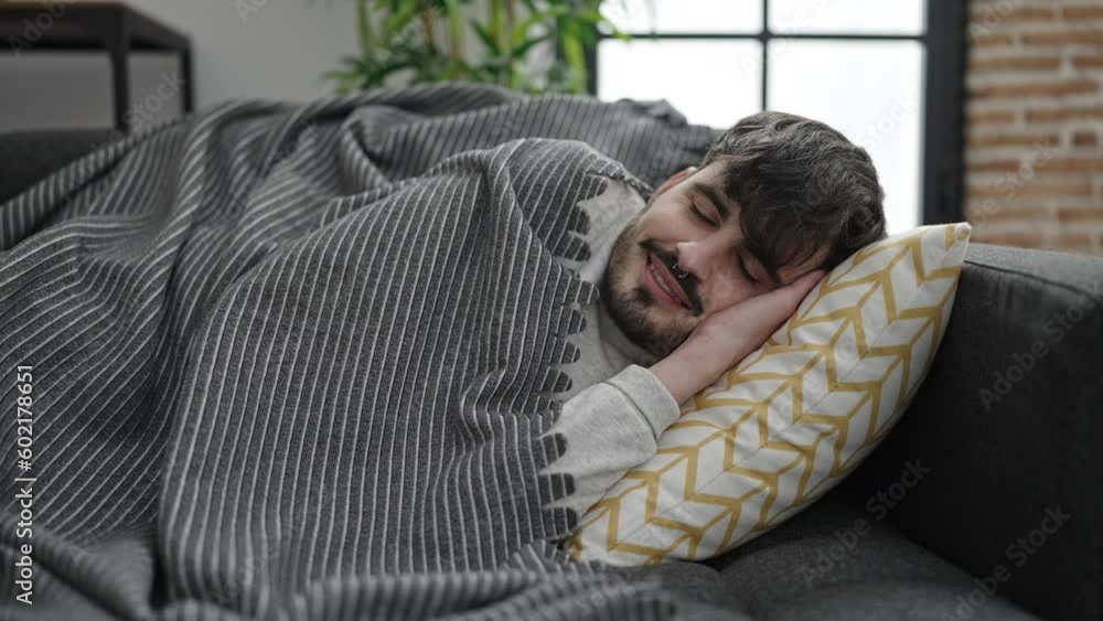 Wall mural Young hispanic man lying on sofa sleeping at home