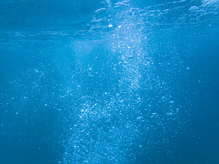 Naklejka premium Underwater background with water bubbles and undersea light rays shine, BUBBLING WATER BACKGROUND, Water bubbles in the sea, Blue ocean waves from underwater with bubbles. Light rays shining through.