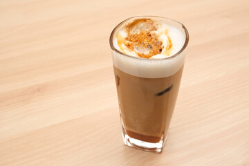 Iced caramel macchiato coffee in glass on wooden table
