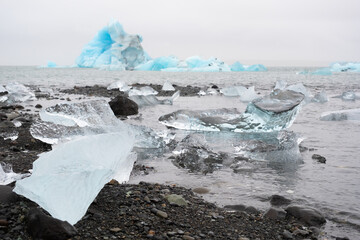 Blue Icebergs in Ocean Water. Glacier Ice Drift at Calm Water. Pure Ice Chunks from Melting Glacier. Icy Winter Landscape. Foggy Weather in Iceland.