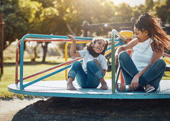 Mother with daughter on roundabout at park, playing together with laughter and fun outdoor. Love,...