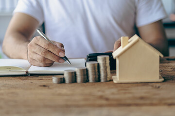 Man's hand holding a coin on a wooden table Save Money and Financial Investment for Home Buying Home Loan Savings Ideas