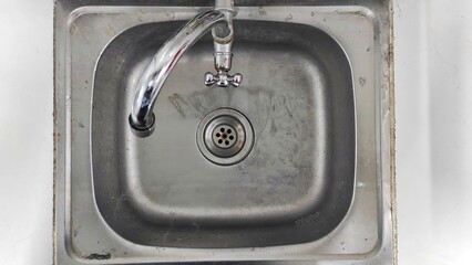 the old dirty metal sink on the white tiled kitchen