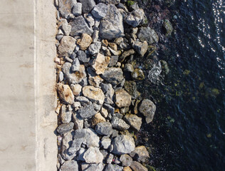 Large granite stones on the river bank. The edge of the river bank, water, road