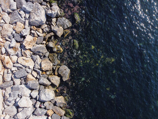 Large granite stones on the river bank. The edge of the river bank, water, road