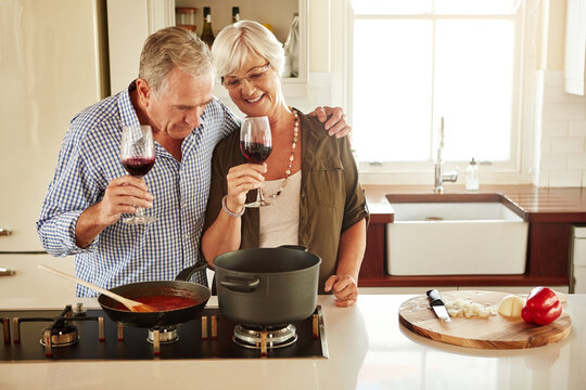 Hug, wine or happy old couple cooking food for a healthy vegan diet together with love in retirement at home. Cheers or senior woman drinking or bonding in house kitchen with mature husband at dinner