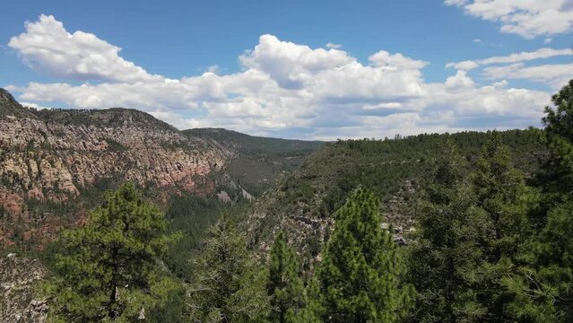 Flying View Over Rock Ledge Toward Forests and Mountains with a Canyon
