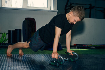 Sporty teenager boy doing push-ups in the gym
