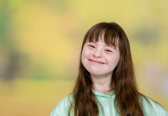 Fototapeta premium Portrait of a happy teen girl with Downs syndrom at summer park. Empty space for text