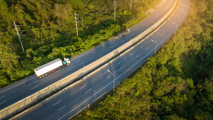 Container Truck with Cargo Trailer Drives on High way the Road aroud mountain forest. Green Cargo Truck on the road in green forest. Concept ecological green transportation
