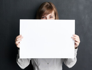 Portrait, poster and mockup with a woman in studio on a dark background for information or announcement. Branding, advertising or marketing with a young female brand ambassador holding a blank sign