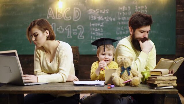 Father and mother teach lovely son to draw and paint. Mother father and son reading the homework on book. Parents feeling proud on progress of child son.