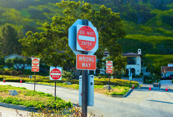 A group of traffic signs emphatically announce DO NOT ENTER and WRONG WAY - obrazy, fototapety, plakaty