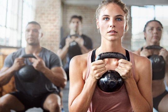 Fitness, exercise and woman with kettlebell in a gym for a strength training challenge. Sports, energy and female athlete doing a workout with weights with her friends or community in wellness center