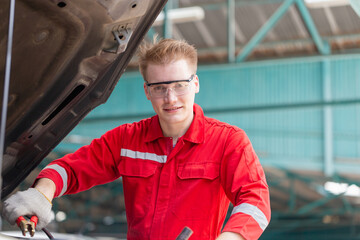 Technicians man with charging cables for car battery, Auto mechanic working in garage, Technician working in auto service, Car repair, and maintenance