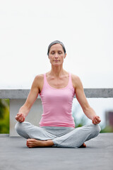 Senior woman, lotus pose and yoga on a floor outdoors for meditation, relax and zen, calm and...