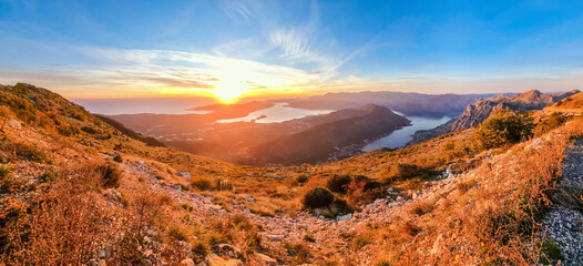 Panoramic photo of the Bay of Kotor taken from mountain at sunset with yellow foreground and blue sky