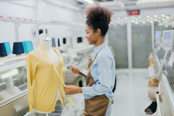 Obraz premium American female designer is designing her clothes and figure with intention There is a tape measure and tablet device. in the weaving industry There was a sewing machine working near her.