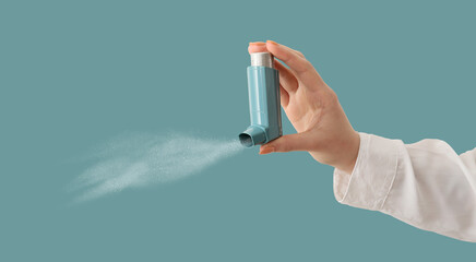 Hand holding inhaler on light blue background