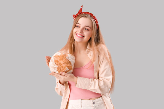 Naklejka Young woman with fresh bread on grey background