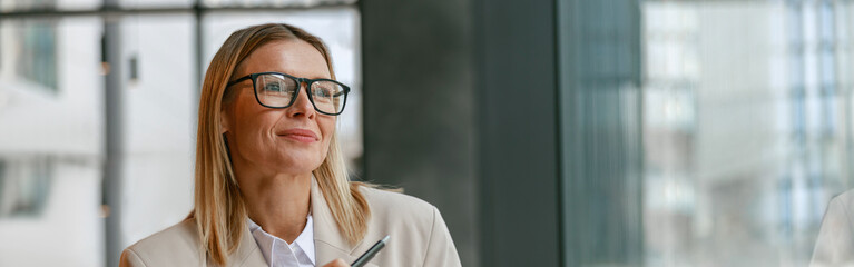 Businesswoman architect in glasses working on project while sitting in cafe and looking at window