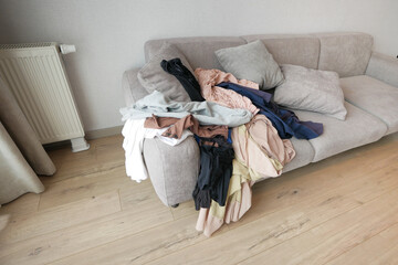 Fototapeta na wymiar Messy clothes on sofa at home 