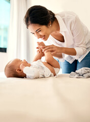 Smile, love and a mother with her baby in the bedroom of their home together for playful bonding. Family, kids and a happy young mama spending time with her newborn infant on the bed for fun or joy