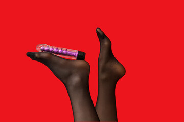 Female legs in stockings with vibrator on red background, closeup
