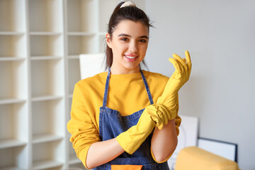 Fototapeta na wymiar Young woman putting on rubber gloves before cleaning her house