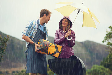 Man, woman and barbecue in rain with umbrella, charcoal or surprise on vacation with love in...