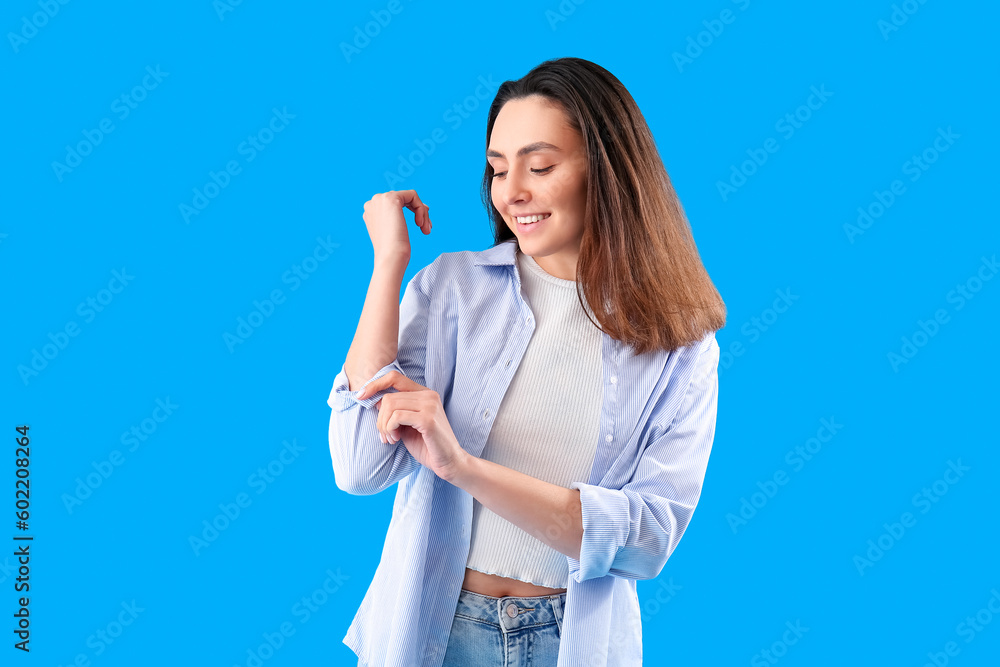 Sticker Beautiful young woman rolling up her sleeve on light blue background