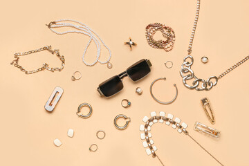 Stylish jewelry with sunglasses on beige background