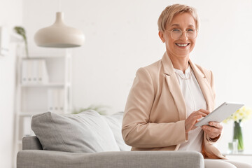 Mature psychologist working with tablet computer in office