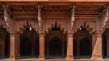 Fototapeta premium The architecture of the ancient Jahangiri Mahal Palace. The colonnade is made of sandstone with carved arches and ornaments. India. Agra. Red Fort.