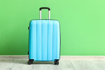 Blue suitcase near green wall