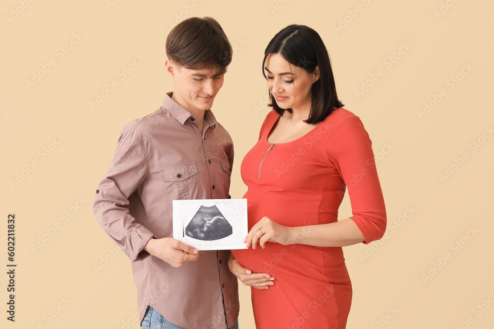 Sticker Young pregnant couple with sonogram image on beige background