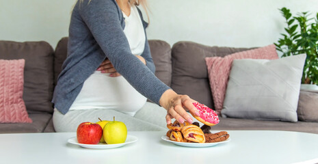 A pregnant woman eats a sweet donut. Selective focus.