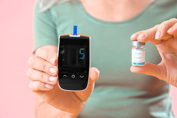 Fototapeta premium Mature diabetic woman with glucometer and insulin on pink background, closeup
