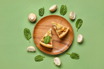 Pieces of mushroom pie with spinach leaves and champignons on green background