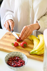 Faceless woman cutting strawberry on chopping board