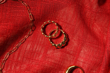 Beautiful rings and chain necklace on red fabric background