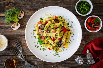 Rigatoni with sliced sausages, parmesan cheese and white mushrooms served on wooden table
