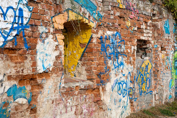 Ancient brick wall painted with poor graffiti