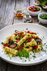 Rigatoni with sliced sausages, parmesan cheese and white mushrooms served on wooden table
