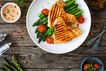 Barbecued turkey breast  and green asparagus on wooden table
