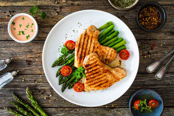 Barbecued turkey breast  and green asparagus on wooden table
