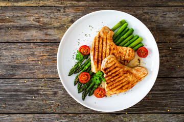 Barbecued turkey breast  and green asparagus on wooden table
