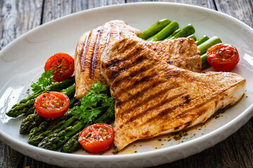 Barbecued turkey breast  and green asparagus on wooden table
