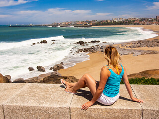 Woman sitting by the sea at Porto viewpoint
